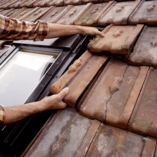 Équipe Lafleur Couvreur remplaçant les tuiles autour d'un Velux sur une toiture de Seine-et-Marne