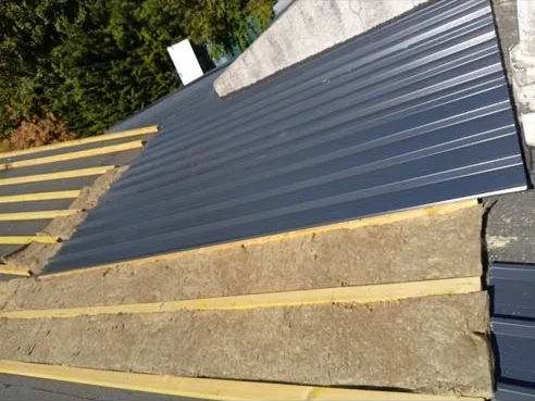 Premiers bacs acier posés sur l’isolation en laine minérale d’un toit de garage