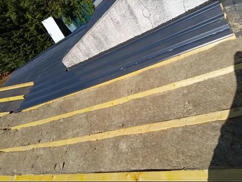 Laine minérale déroulée entre les chevrons avant la pose des bacs acier