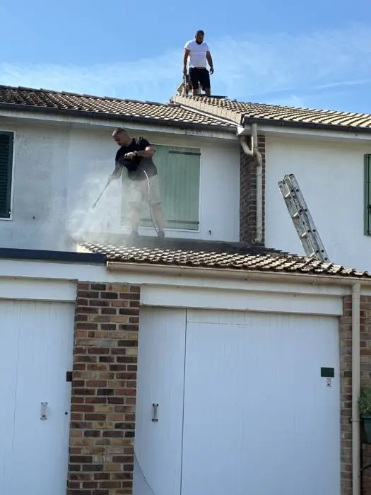 Deux couvreurs de Lafleur Couvreur nettoient la toiture en tuiles béton à haute pression à Guermantes