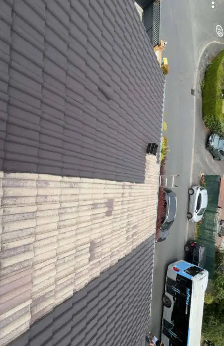 Vue en hauteur de la toiture en tuiles béton de Guermantes, versant repeint et versant délavé côte à côte